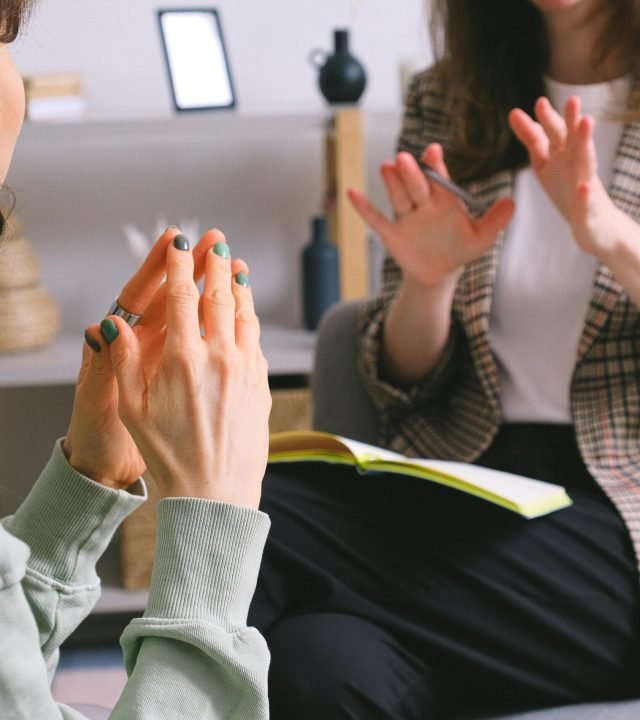 Two women engaged in a therapy session, communication and support in an office setting.